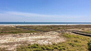 A coastal landscape with a sandy beach, a wooden boardwalk, and a clear blue sky. - Family Condo: Resort Pool Access & Ocean View (Dauphin Island)