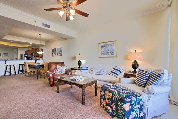 A spacious living room with a dining area, a ceiling fan, and a kitchen in the background. - Family Condo: Resort Pool Access & Ocean View (Dauphin Island)