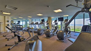 A gym with cardio machines, weight equipment, and large windows offering a view. - Family Condo: Resort Pool Access & Ocean View (Dauphin Island)