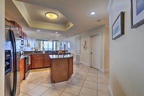 A spacious kitchen with a central island, wooden cabinets, stainless steel appliances, and a tiled floor. - Family Condo: Resort Pool Access & Ocean View (Dauphin Island)