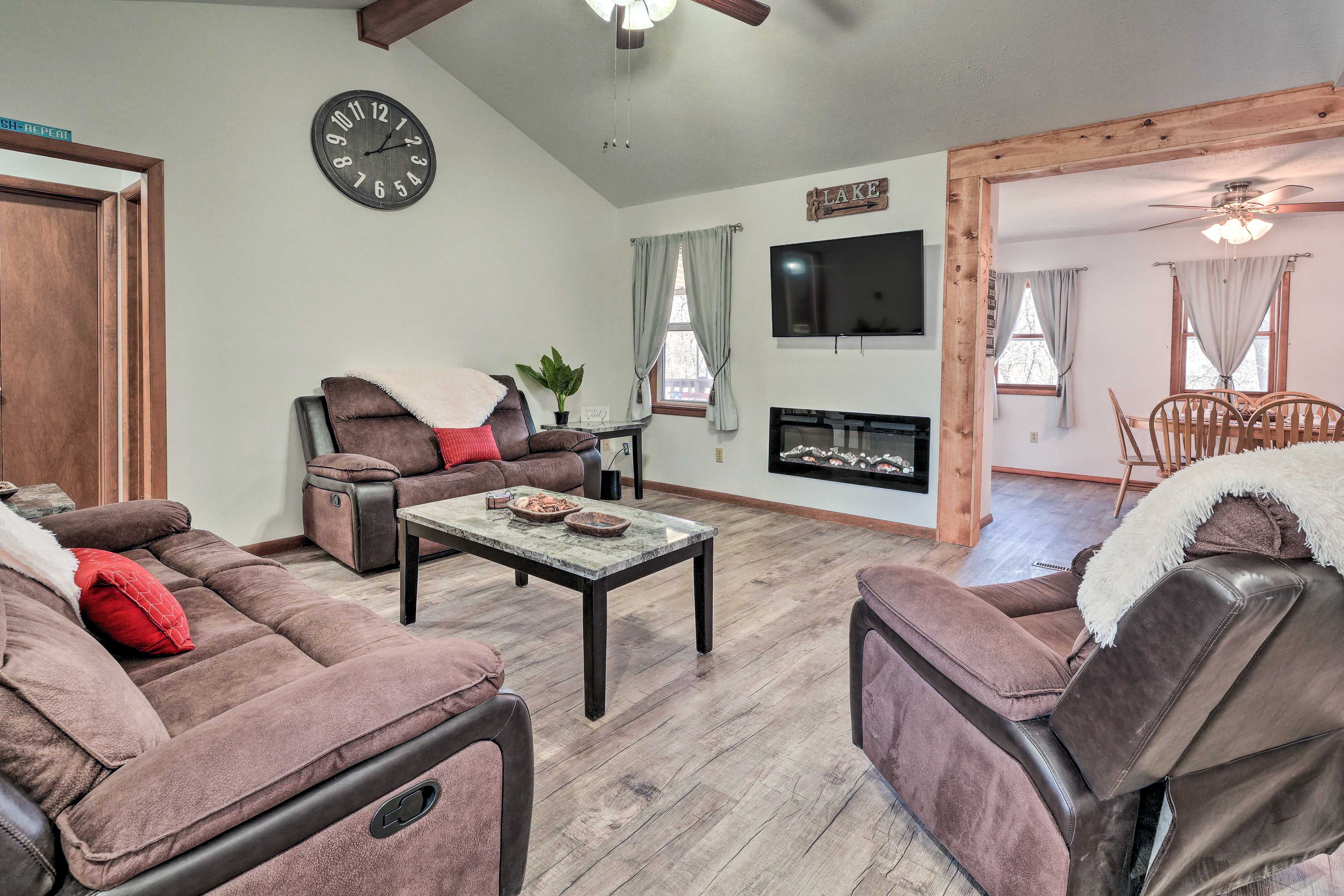 A living room with a sofa set, a coffee table, a fireplace, and a TV mounted on the wall.