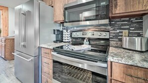 A modern kitchen with stainless steel appliances, wooden cabinets, and a patterned backsplash.