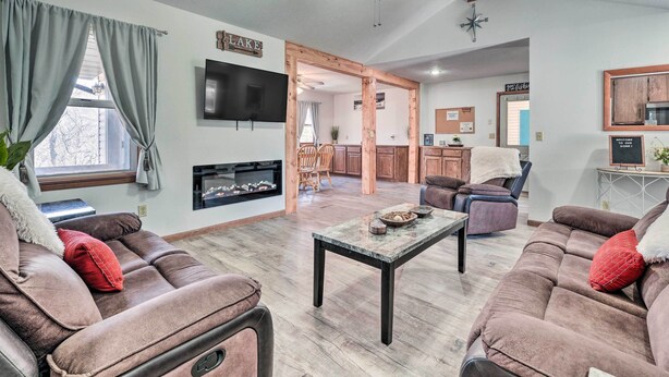 A spacious living room with a fireplace, a dining area, and a kitchen visible through an open doorway.