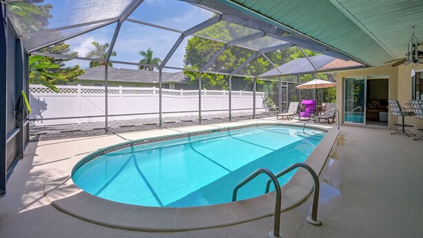 Piscina coberta ao ar livre com vista para uma área residencial, incluindo uma casa e um muro.