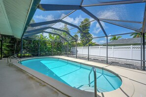A swimming pool with a clear blue water surface, surrounded by a metal fence and a covered area with a roof. - Marco Island Retreat w/ Pool ~ 1 Mi to Beach (Marco Island)