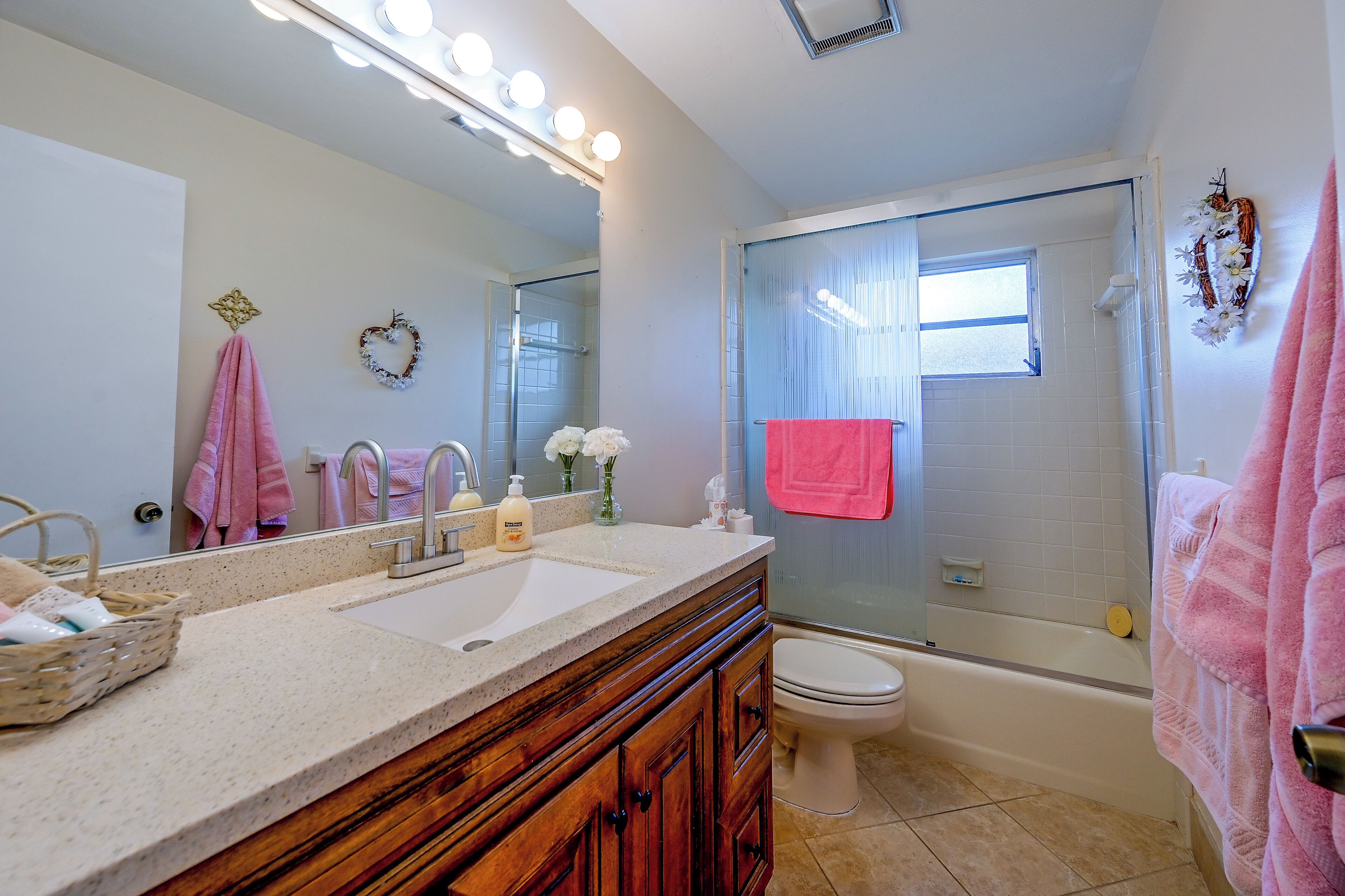 A bathroom with a vanity, sink, mirror, and a shower area.