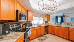 A kitchen with wooden cabinets, a microwave, a toaster, and a chandelier.