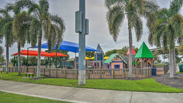 A playground with colorful play structures, surrounded by palm trees and covered by blue and red umbrellas. - Marco Island Retreat w/ Pool ~ 1 Mi to Beach (Marco Island)
