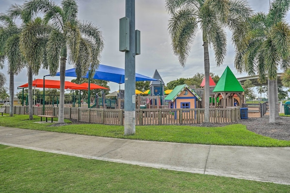 Ein Spielplatz mit bunten Spielgeräten und Palmen.