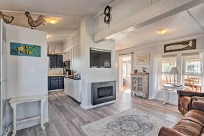 Een ruime woonkamer met een open haard, een eethoek met een tafel en stoelen, en een keuken met moderne apparatuur.