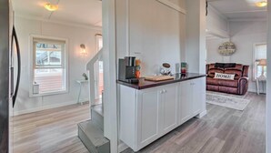 A modern kitchen with white cabinetry, a coffee machine, and a wooden countertop.