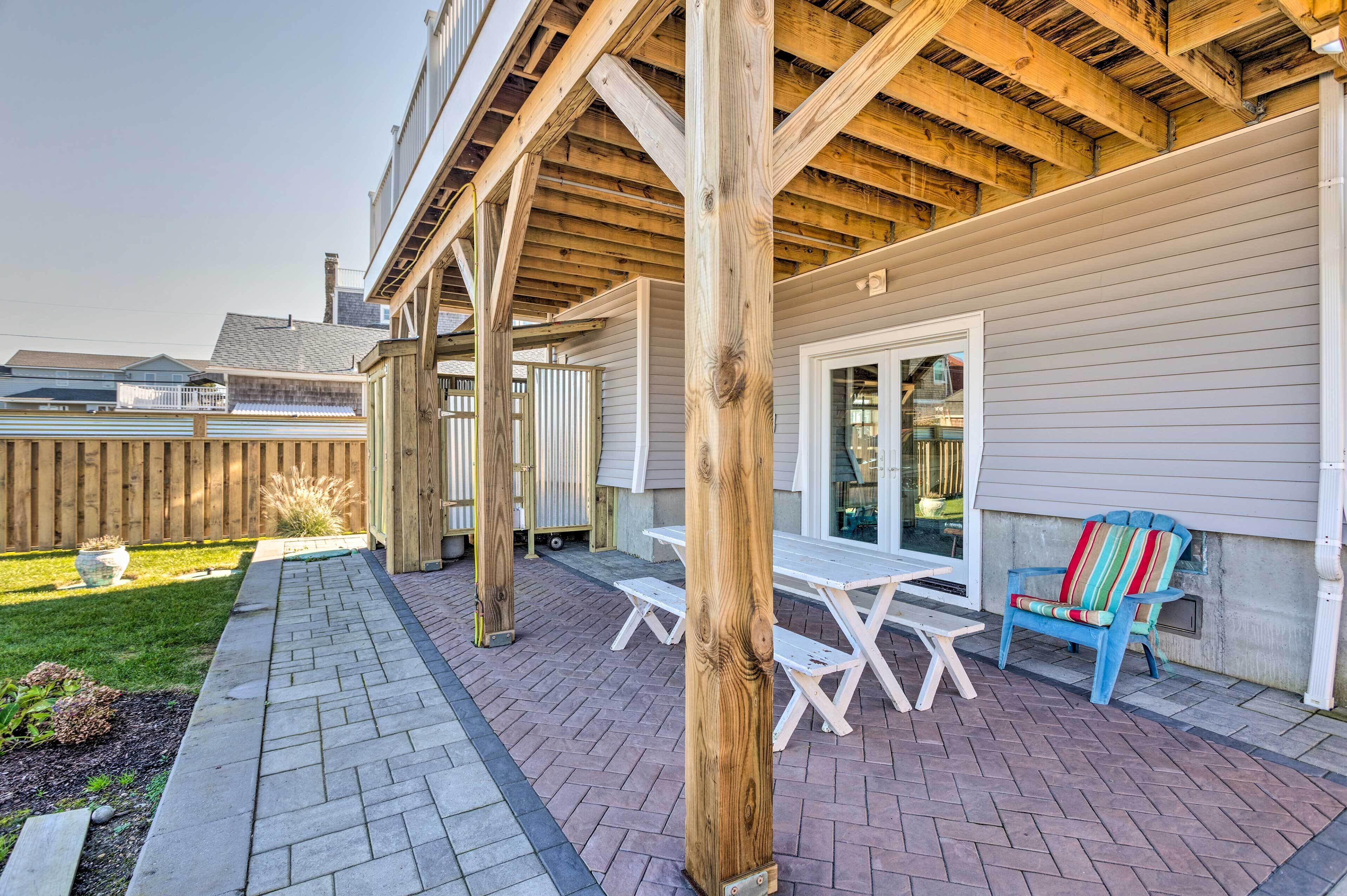 A covered patio with wooden beams, a white table and chairs, and a colorful Adirondack chair.