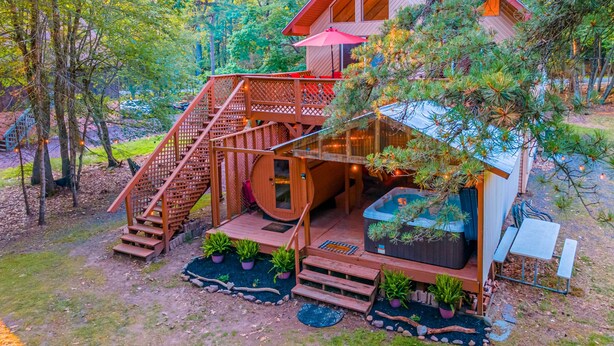 A cabin with a wooden deck, a hot tub, and a staircase leading to a balcony. - 3 Mi to Slopes! Poconos Chalet w/ Hot Tub & Sauna (Lake Harmony)