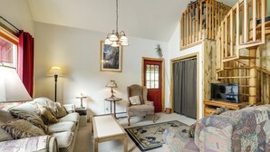 Una sala de estar con sofá, sillón, mesa y televisor sobre un mueble de madera.