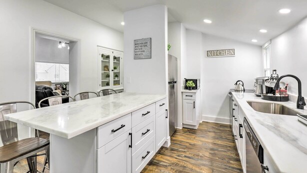 A modern kitchen with white cabinetry, a marble countertop, and a built-in dishwasher. - Charming Home ~ 7 Mi to Thanksgiving Point (American Fork)