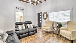 A living room with a black leather sofa, beige armchairs, and a chandelier. - Charming Home ~ 7 Mi to Thanksgiving Point (American Fork)