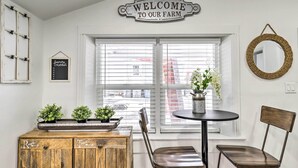 A farmhouse interior with a 'Welcome to our farm' sign, a wooden cabinet with plants, a round table with chairs, and a woven mirror. - Charming Home ~ 7 Mi to Thanksgiving Point (American Fork)