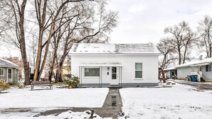 A small, single-story building with a white exterior and a gray roof, surrounded by snow-covered ground and leafless trees. - Charming Home ~ 7 Mi to Thanksgiving Point (American Fork)