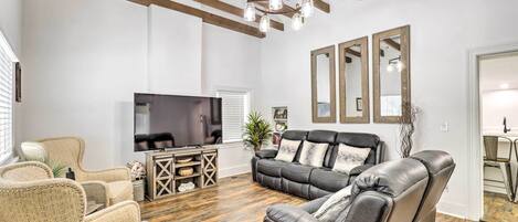 A living room with a leather sofa, a television, and a wooden ceiling.
