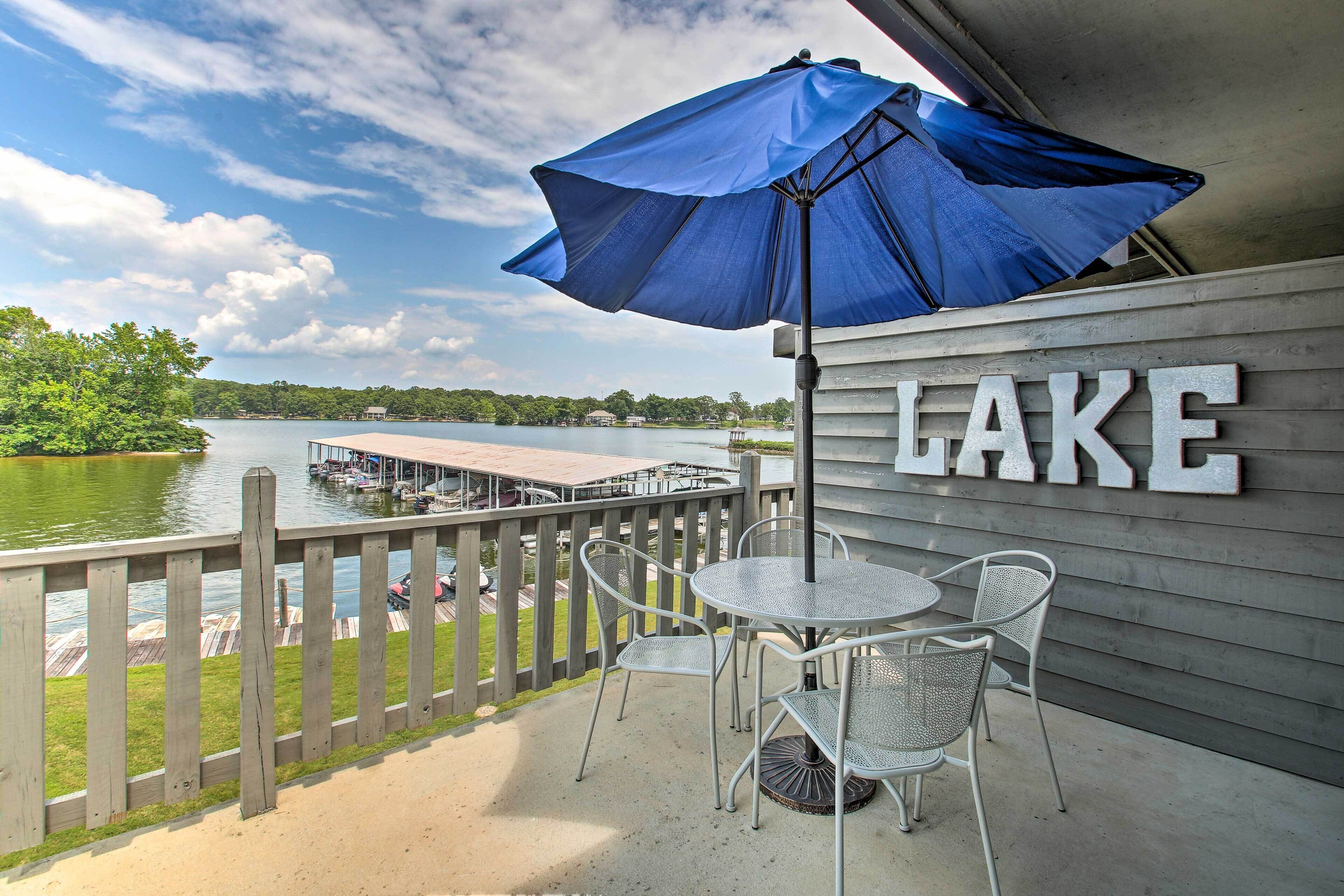 Un balcon donnant sur un lac, un parasol bleu et une pancarte sur laquelle on peut lire « LAC ».