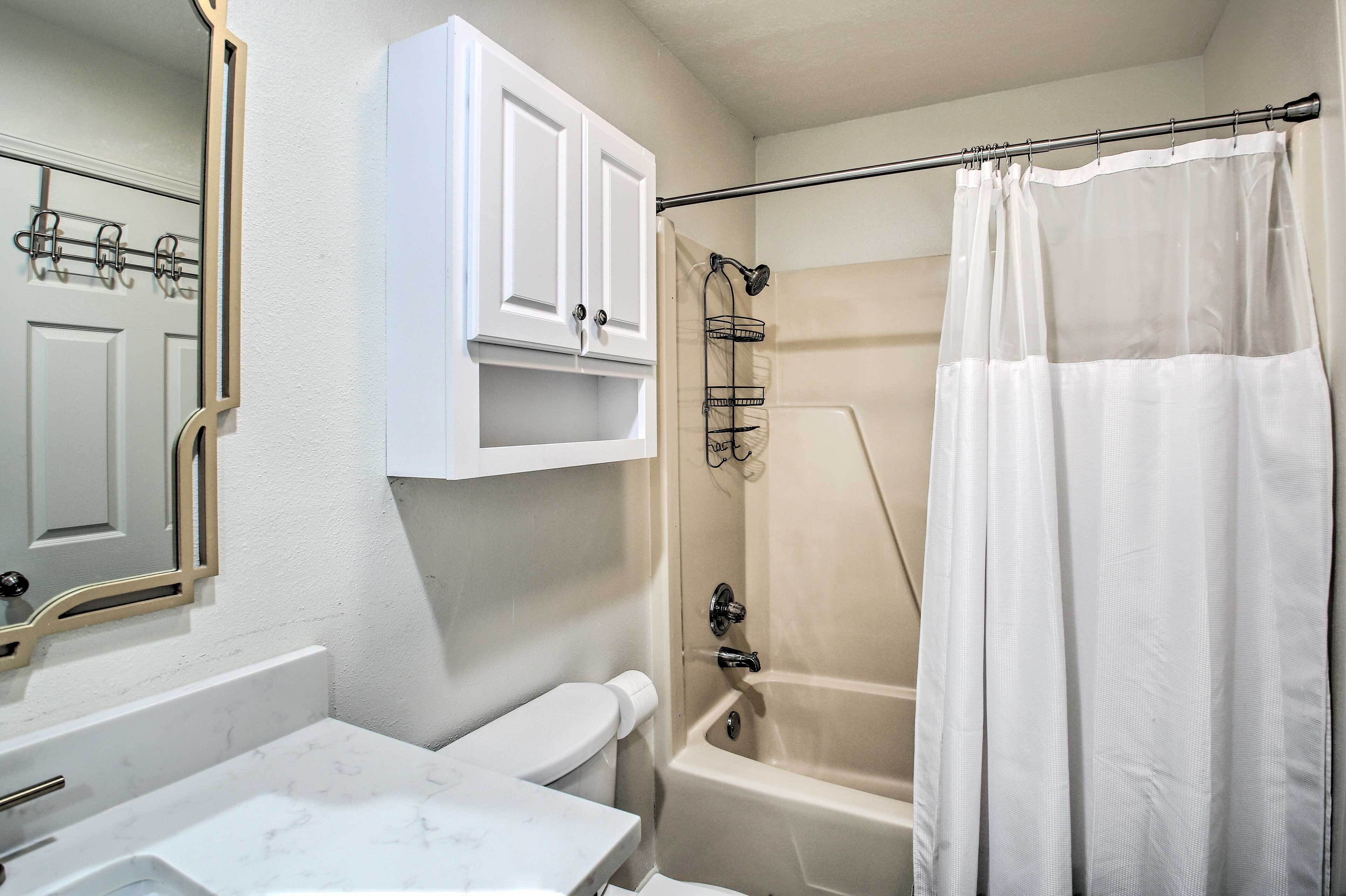 A bathroom with a toilet, sink, bathtub, and a shower curtain.