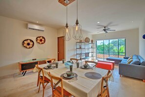 Comedor con una mesa dispuesta para cuatro, sillas e iluminación colgante.