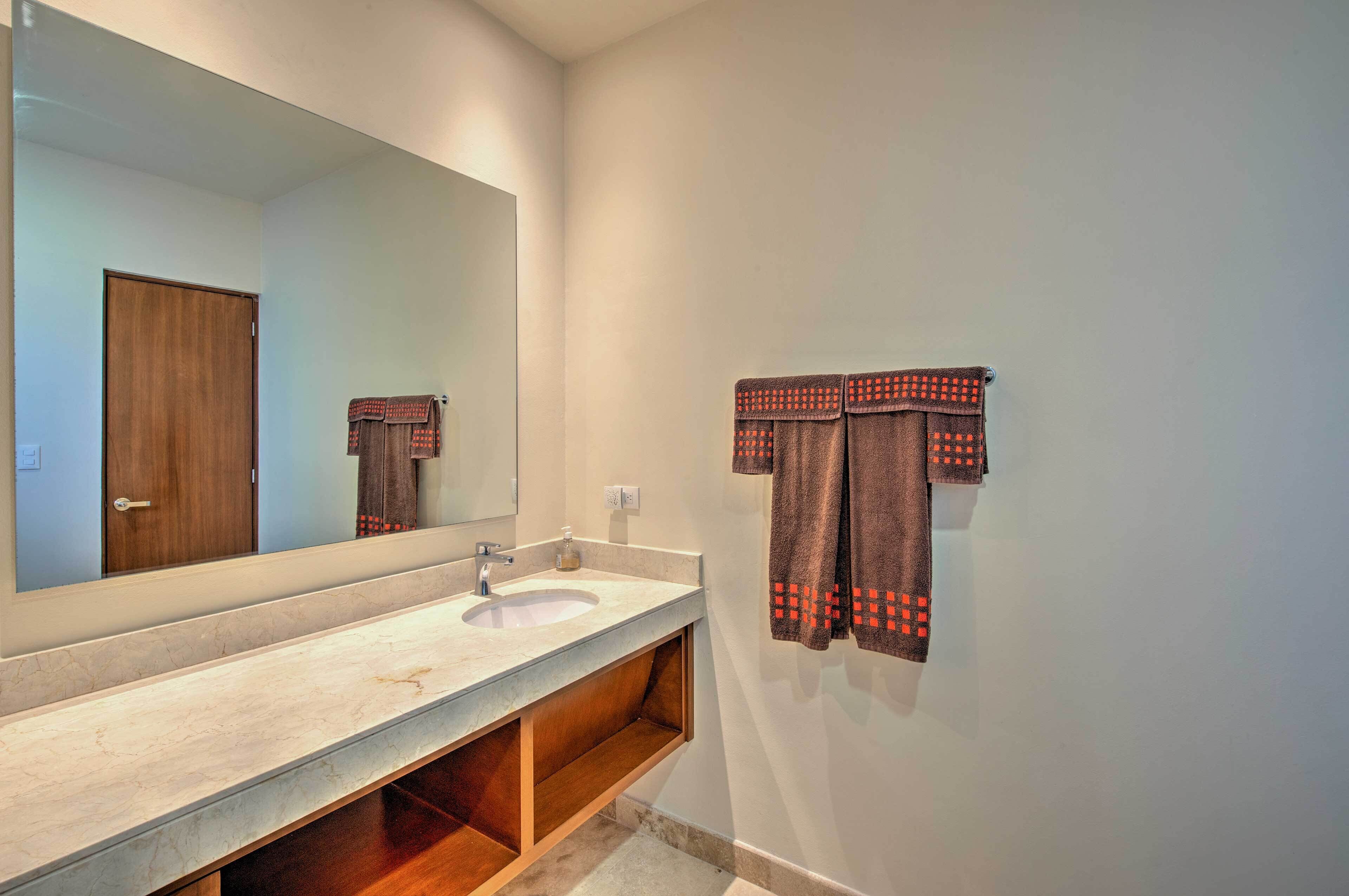 A bathroom with a marble sink, wooden vanity, and a large mirror.