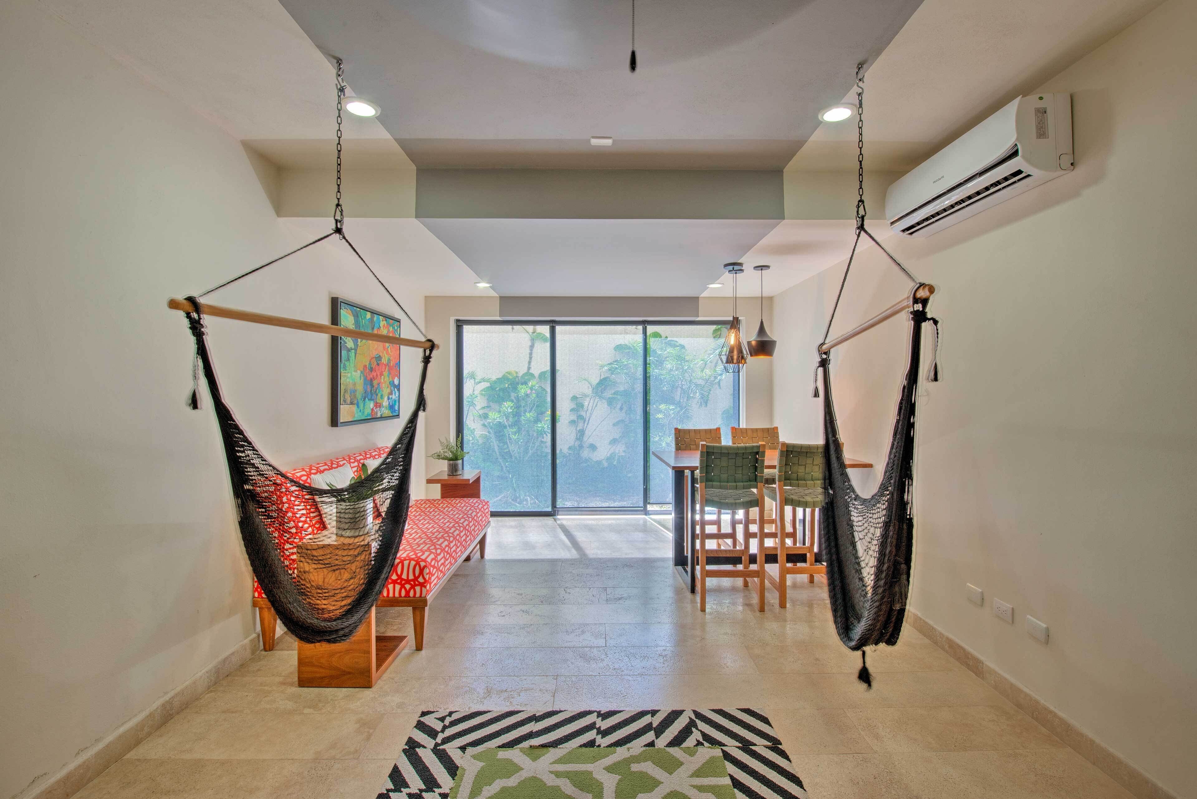Una habitación amplia con un gran ventanal, un comedor y dos hamacas.
