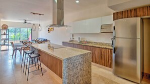 A modern kitchen with a granite island, stainless steel appliances, and wooden cabinetry. - Resort-style Condo 3 Miles to Historic Tulum Ruins (Tulum)