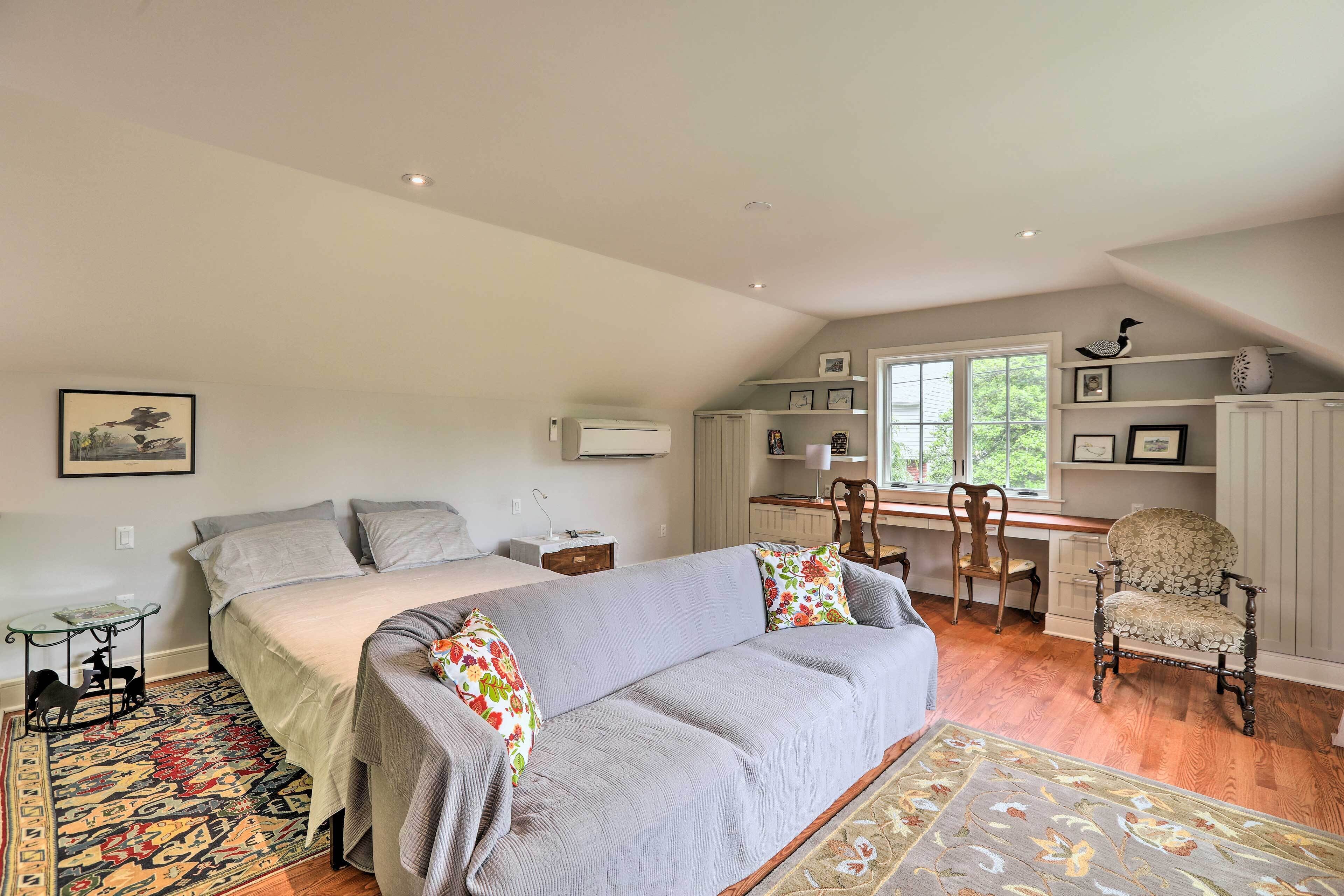 A bedroom with a large bed, a desk, a chair, and a decorative chair.