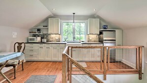 Een moderne keuken met witte kastjes, een houten eettafel en uitzicht op het omliggende landschap door grote ramen.