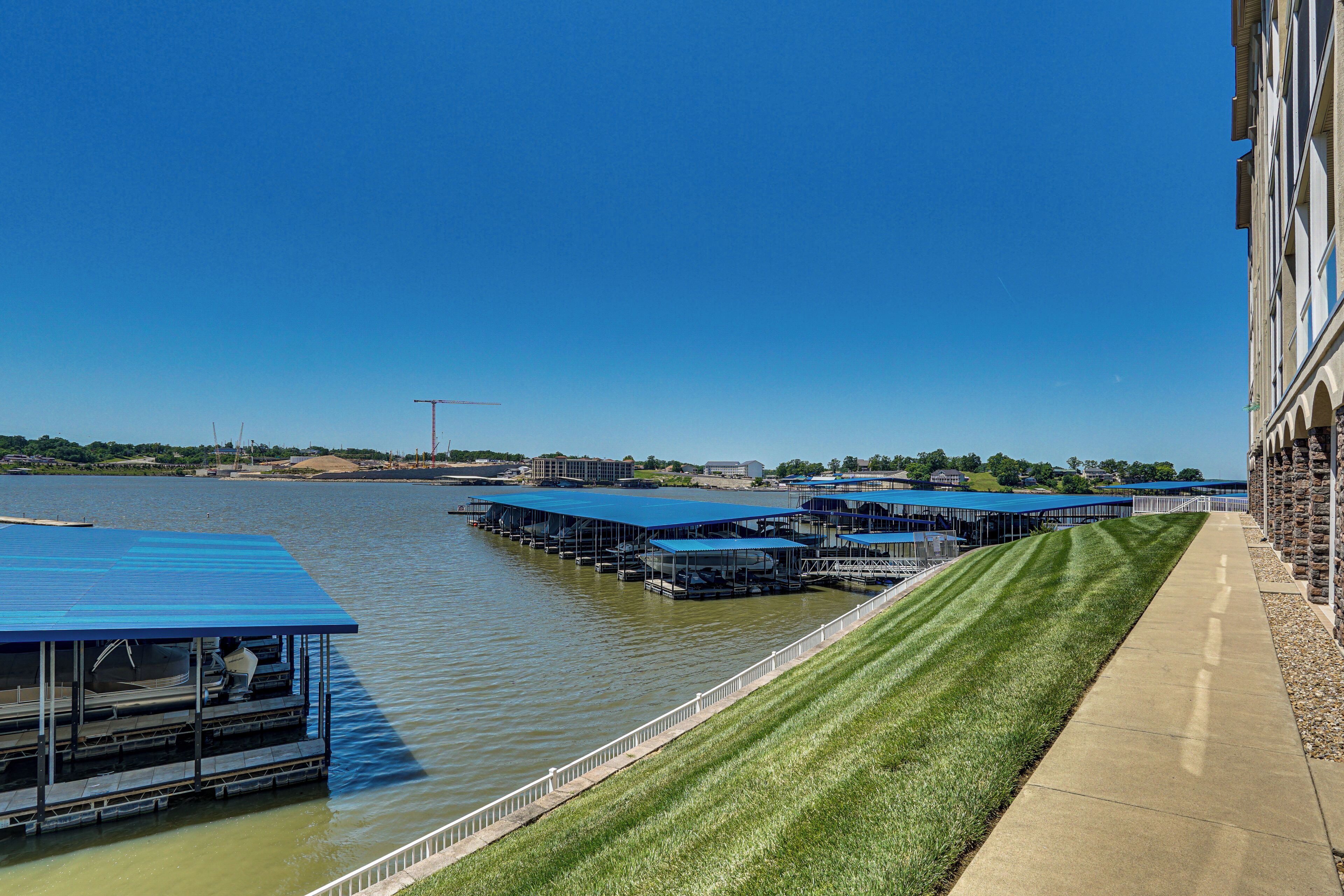 A waterfront property with a dock, covered seating areas, and a grassy walkway.