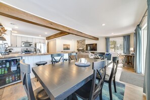 Een moderne keuken met witte kasten, een inbouwmagnetron en een koelkast. Er is een eethoek met een donker houten tafel en stoelen.