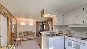 A compact kitchen with white cabinets, a built-in microwave, and a stove.