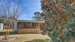 A single-story wooden cabin with a porch, surrounded by a well-maintained lawn and trees.