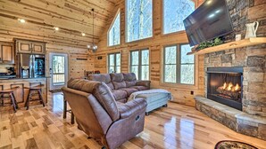 A spacious living room with a large sectional sofa, a fireplace, and a kitchen area with a bar. - Hot Tub & Game Room: Mountaintop Cabin in Murphy! (Murphy)