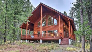 A wooden cabin with a balcony, surrounded by trees.