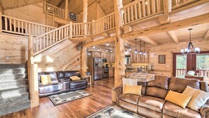 Ein geräumiges Blockhaus-Interieur mit einer Holztreppe, Ledersofas, einem Essbereich und einer Küche.