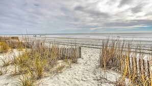 En strand med sand, tång och ett trästaket.