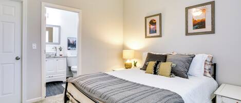 A bedroom with a bed, a nightstand, a ceiling fan, and two wall-mounted pictures.