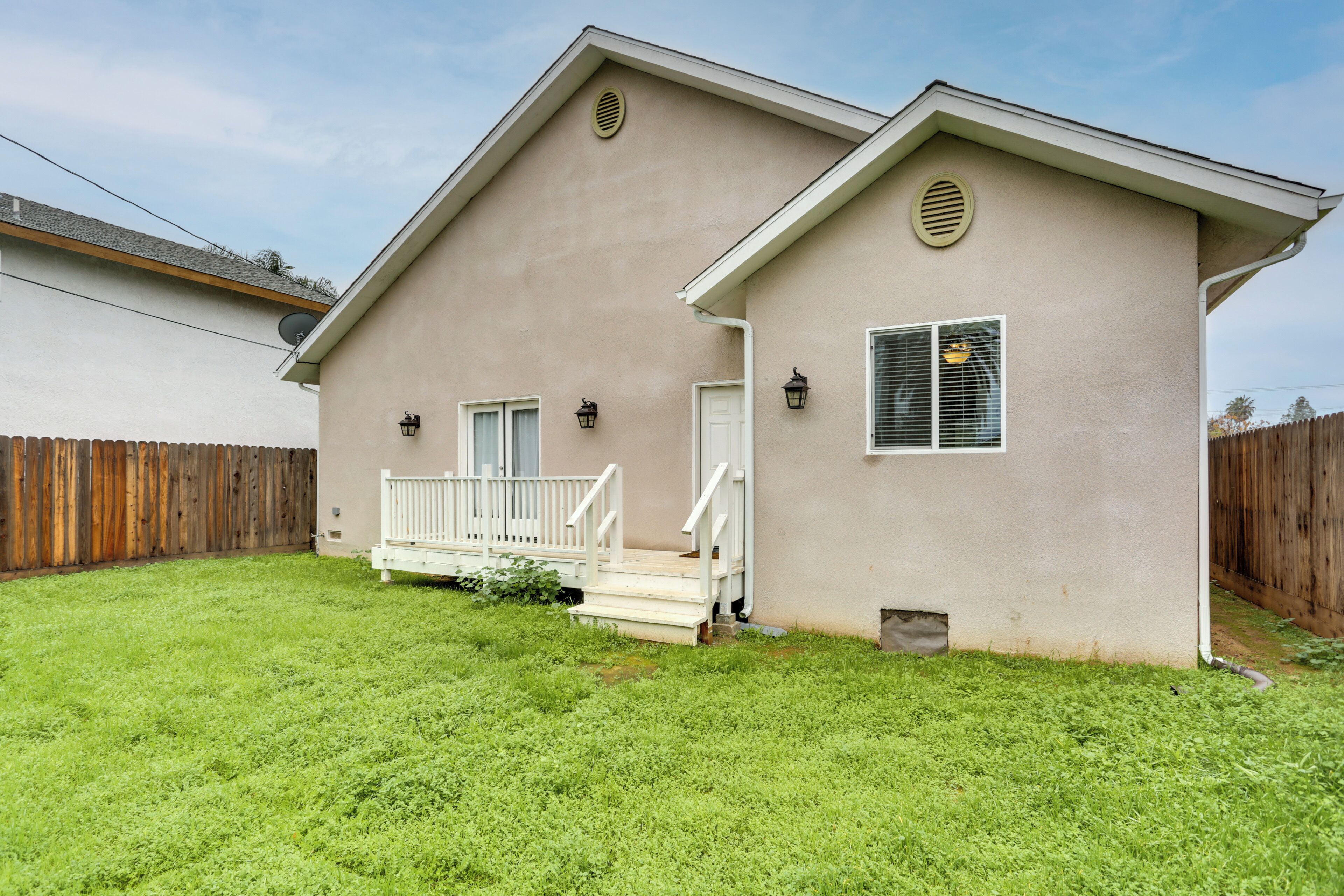 A single-story house with a front porch, a small deck, and a fenced backyard.