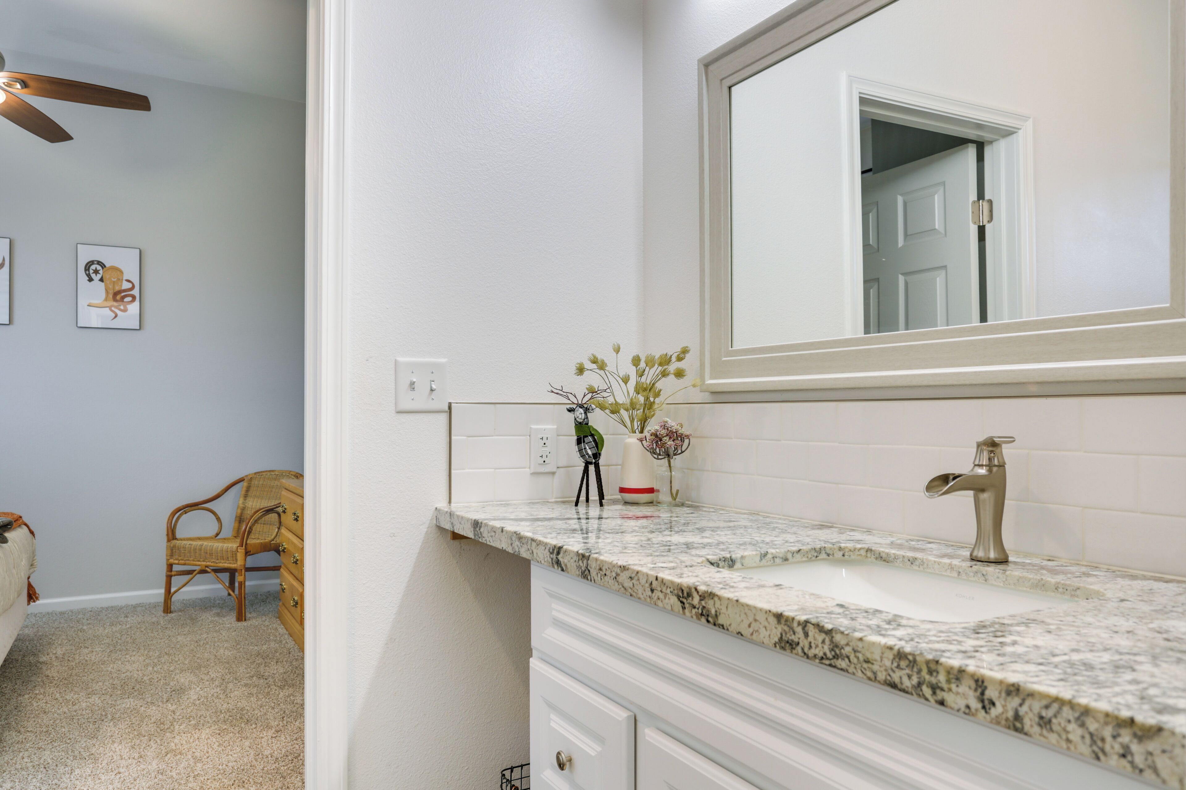 Une salle de bain avec un meuble-lavabo blanc, un  évier, un miroir et un ventilateur de plafond.