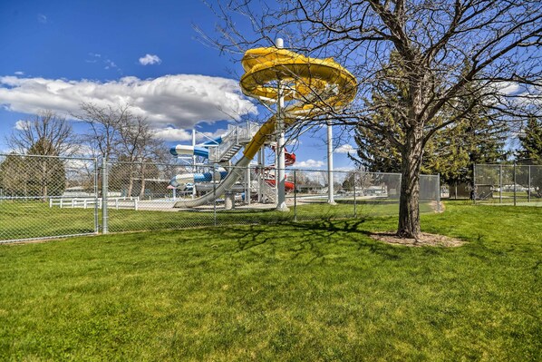 A playground with a yellow spiral slide and a tree in the foreground.