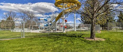 A playground with a yellow spiral slide and a tree in the foreground.