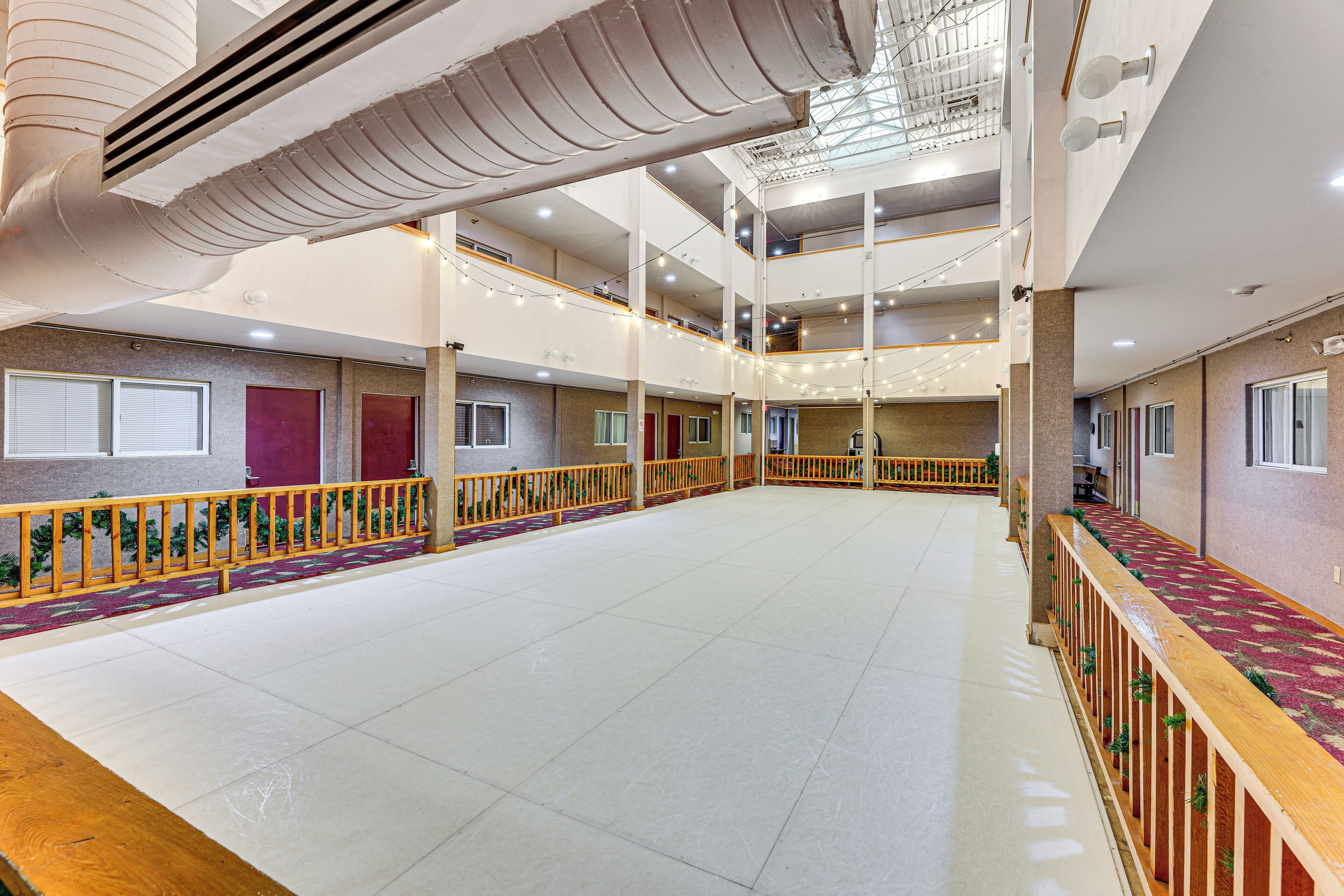A spacious indoor area with multiple balconies, railings, and a high ceiling with visible ductwork.