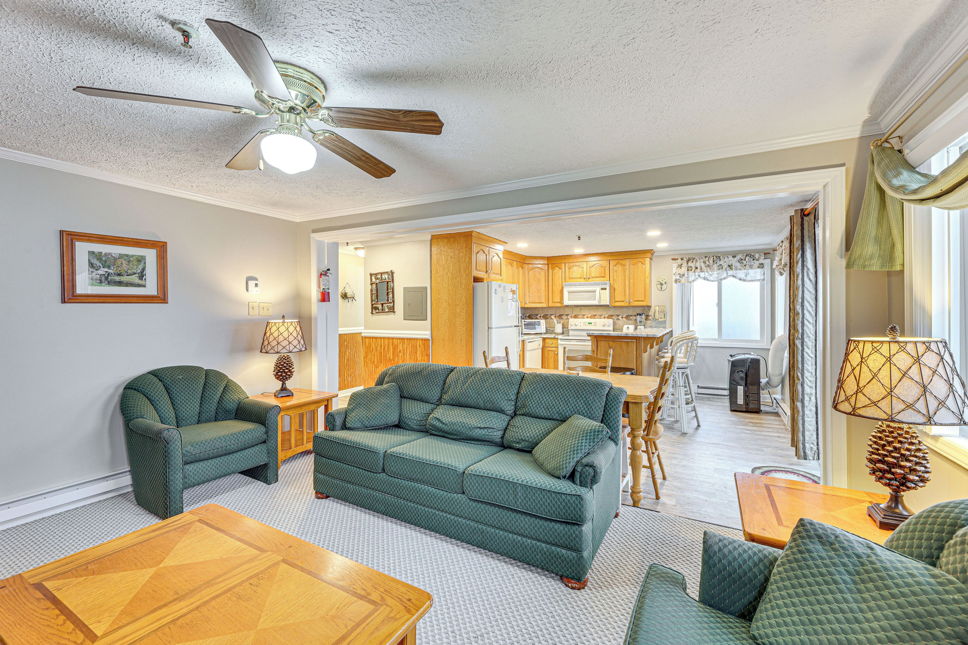 A living room with a green sofa, wooden coffee table, and a ceiling fan.