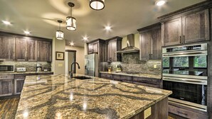 Una cocina moderna con encimeras de granito, electrodomésticos de acero inoxidable y armarios de madera oscura.