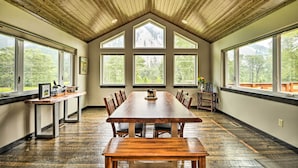 Un amplio comedor con techo de madera alto y ventanas grandes que ofrecen vistas al exterior.