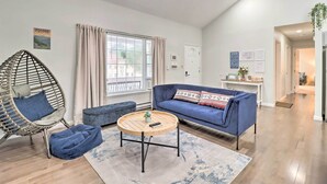 A modern living room with a blue sofa, a wicker chair, and a round coffee table. - Gas Grill, Lake Access: Scenic Poconos Retreat! (East Stroudsburg)
