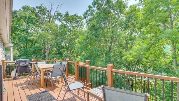 A wooden deck with outdoor furniture, including a table and chairs, surrounded by a railing. - Gas Grill, Lake Access: Scenic Poconos Retreat! (East Stroudsburg)